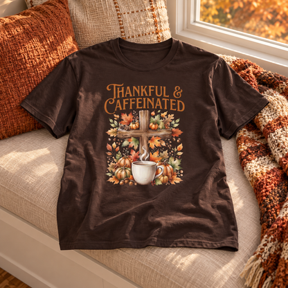 Dark Brown Thankful & Caffeinated Shirt — no person, shirt laid naturally front fully visible on a linen upholstered window bench, warm fall afternoon light